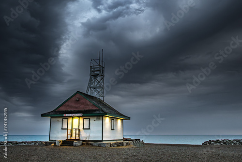 dark moody thunder storm clouds fill the sky over a wooden lifegaurd station shot after sundown on kew beach in toronto room for text