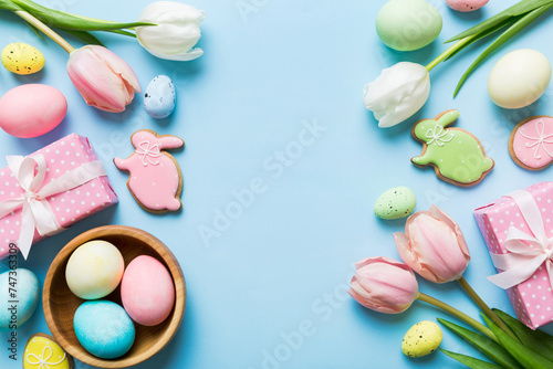 Easter frame with eggs, gift box and tulip on a colored background. The minimal concept. Top view Happy Easter composition. Card with a copy space of the place for the text