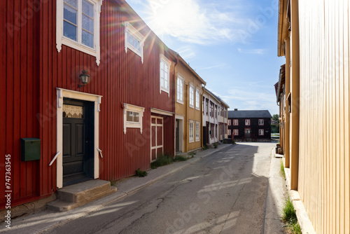 Warm sunbeams grace a cozy street in Roros, casting light on the colorful facades of the historic wooden houses that embody the town's rich cultural tapestry
