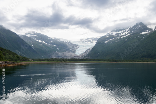 Svartisen Glacier s grandeur is mirrored in the still waters of the fjord  a serene reflection of Norway s dynamic landscape and glacial beauty