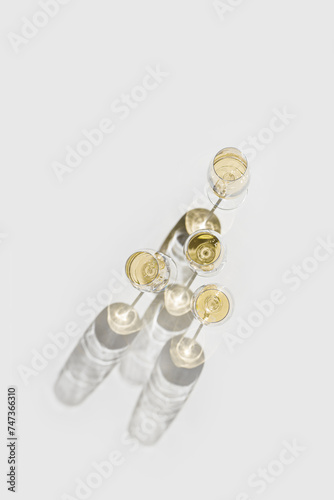Set of glasses of white wine at wine tasting, Minimal trend concept. Top view shiny wineglass standing on table at sunlight, shadow and sun flare, alcohol drinks on white grey background, copyspace