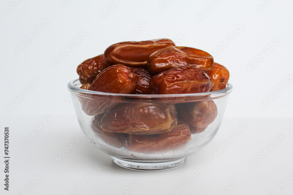Deglet noor or deglet nour or date palm or dates, in a transparent bowl, isolated on white background