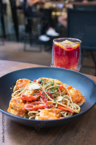 Close-up of spaghetti with shrimp served with a glass of fruit drink in the restaurant.