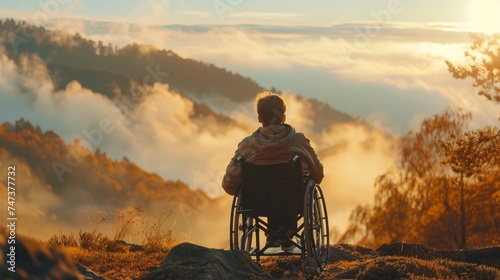 Man in wheelchair mountain range with fog with morning sunlight