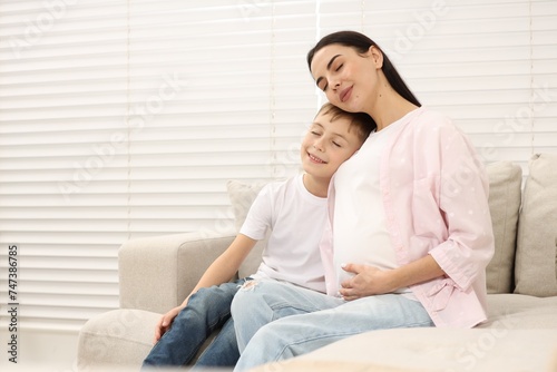 Pregnant woman with her son at home, space for text