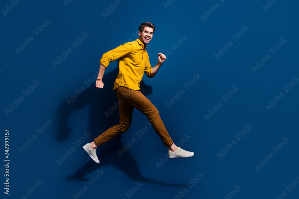 Full length photo of nice young male jumping run black friday promo wear trendy yellow garment isolated on dark blue color background