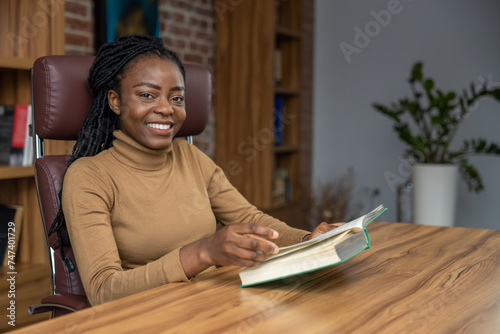 Woman sitting at table reading book student deepening her knowledge for educational purposes