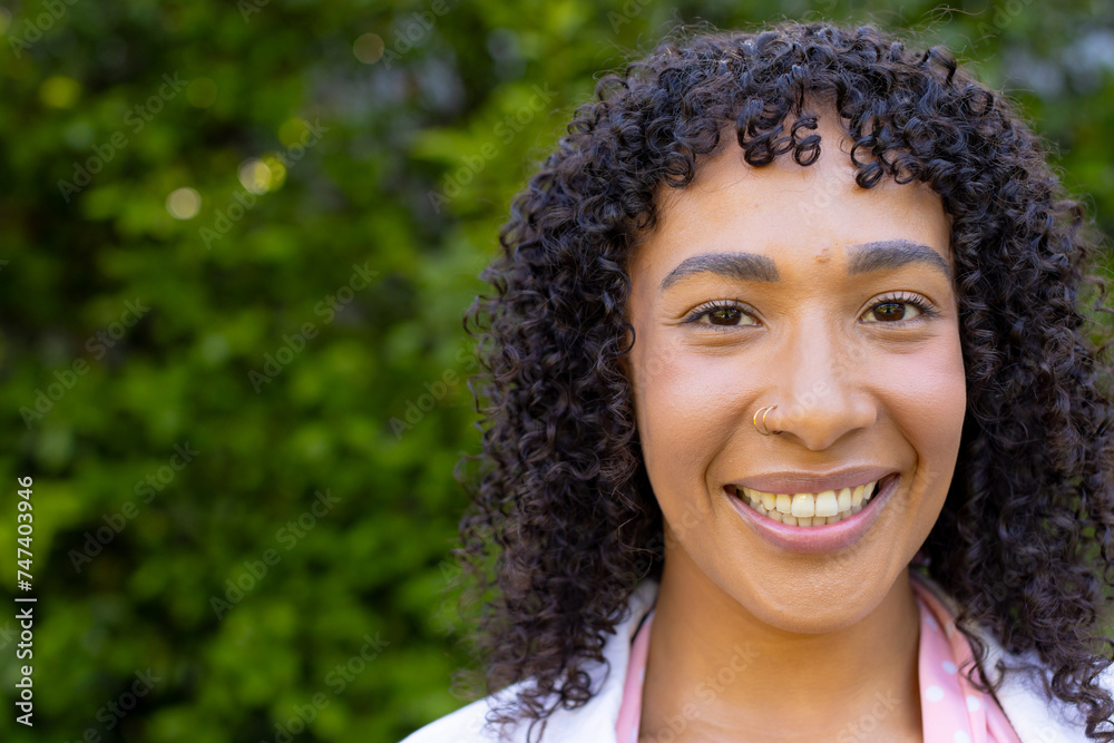 Young biracial woman with curly hair smiles brightly at home, wearing a pink scarf, with copy space Young biracial woman with curly hair smiles brightly at home, wearing a pink scarf, with copy space