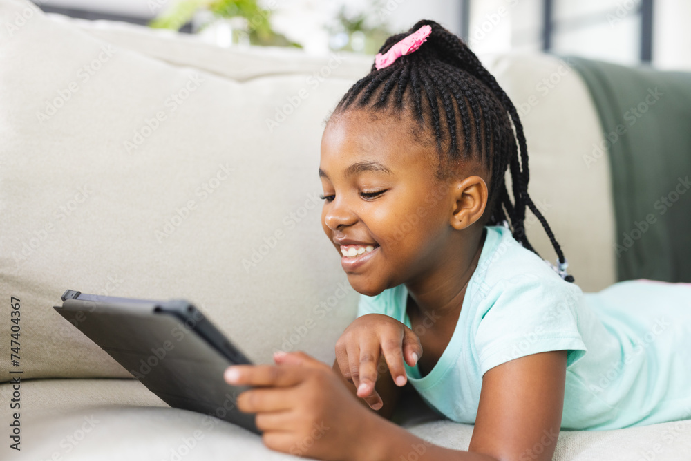 African American girl with braided hair is using a tablet on the couch African American girl with braided hair is using a tablet on the couch