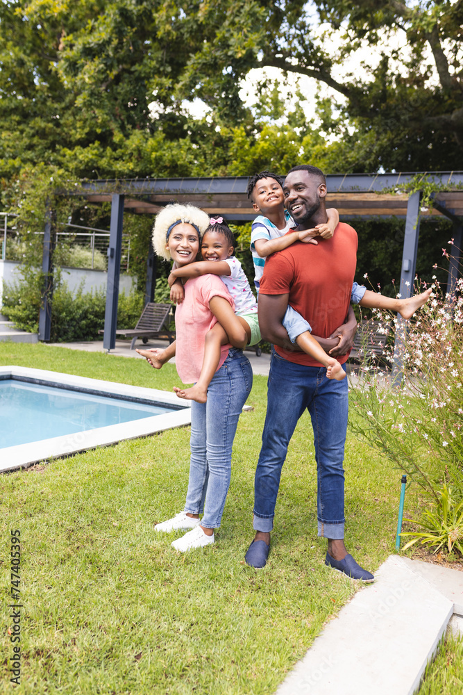 African American man with a beard is giving a piggyback ride to a boy, while a young biracial woman African American man with a beard is giving a piggyback ride to a boy, while a young biracial woman