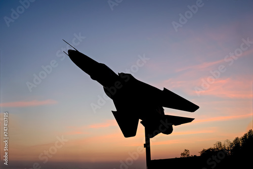 Sun rises behind silhouette image of Indian Air Force's fighter jet plane MIG-29 displayed at NDA chowk in Pune. photo