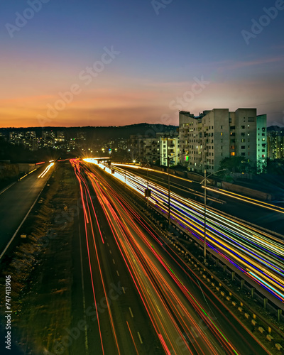 Φωτογραφία Slow shutter speed image of light trails, beautiful sunset sky , buildings and flowing traffic on motorway