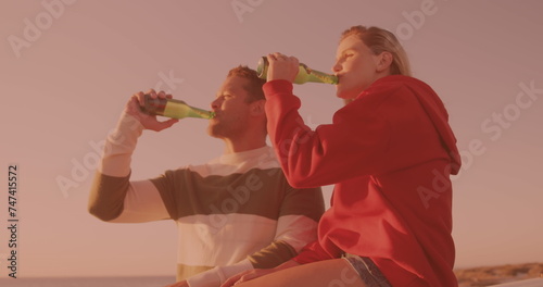 Caucasian couple toasting and drinking beers together at the beach