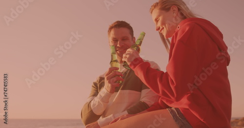 Caucasian couple toasting and drinking beers together at the beach