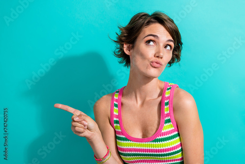 Portrait of cute promoter lady direct finger empty space interesting billboard information isolated teal color background
