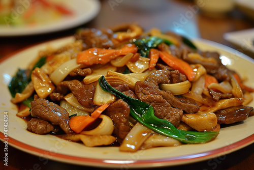 A plate of chow fun, a dish of stir-fried wide rice noodles, beef, and vegetables photo