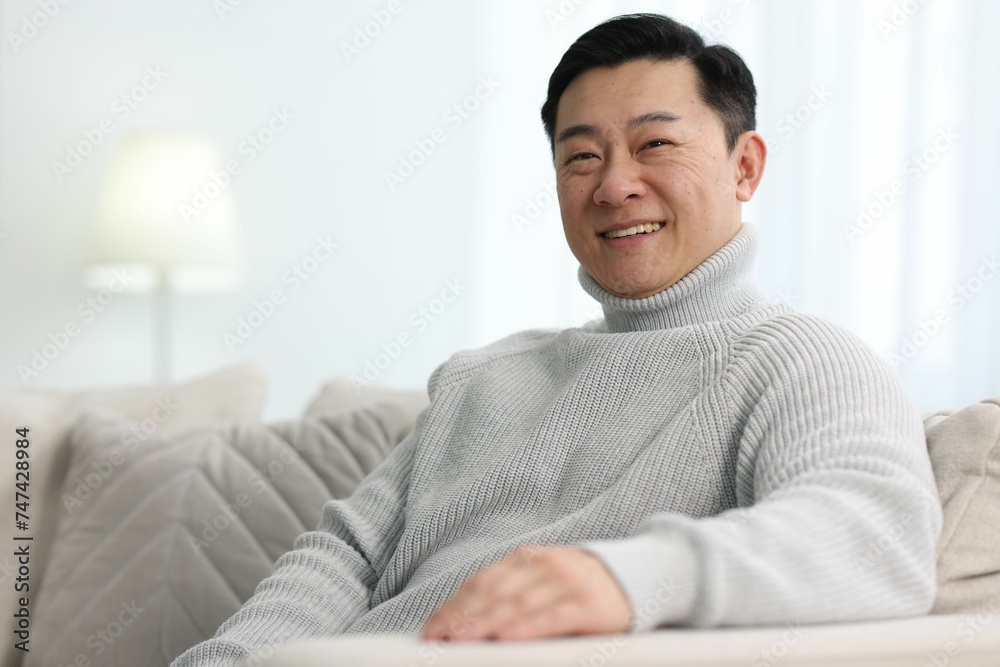 Portrait of smiling man on sofa indoors. Space for text Portrait of smiling man on sofa indoors. Space for text