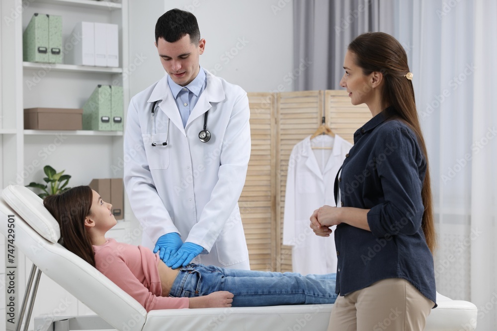 Gastroenterologist examining girl with stomach ache on couch in clinic Gastroenterologist examining girl with stomach ache on couch in clinic