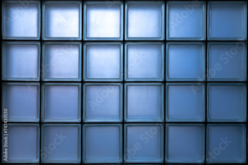 Window is made of a blue glass block glowing from the inside. Glass block wall pattern.