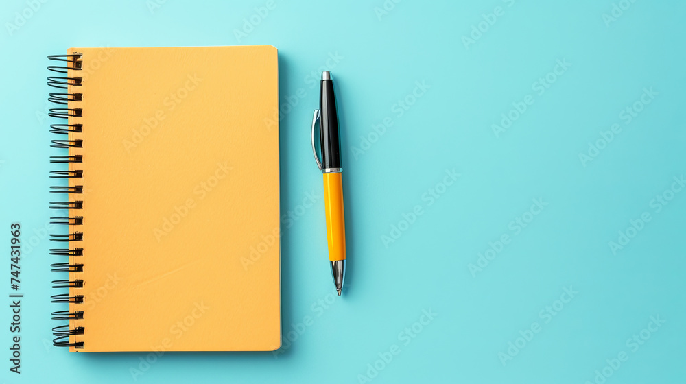 Top view of notepad with pen lying on blue background Top view of notepad with pen lying on blue background