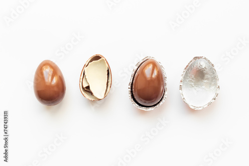 Chocolate eggs broken on white background. Chocolate sweets, top view