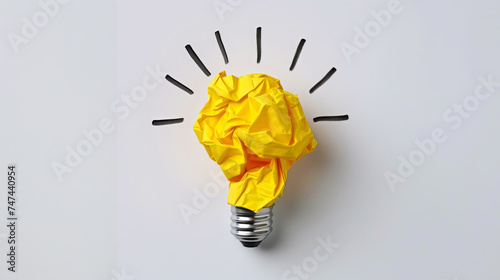 A crumpled piece of yellow paper forms the shape of a lightbulb against a white background, symbolizing a bright idea or creative concept.