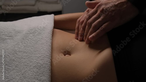 Male hands doing lymphatic drainage massage on a female stomach.