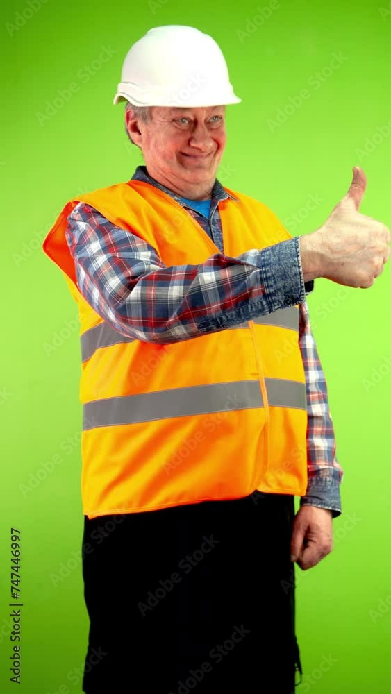 Senior builder in vest and helmet makes perfect gesture and shows thumbs up. Senior builder in vest and helmet makes perfect gesture and shows thumbs up.