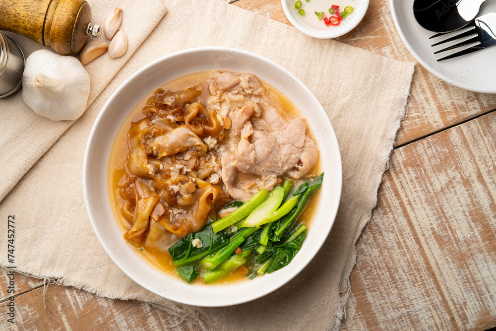Flat Noodles with Marinated Pork and Collard greens in Gravy Sauce in white plate.Top view Flat Noodles with Marinated Pork and Collard greens in Gravy Sauce in white plate.Top view
