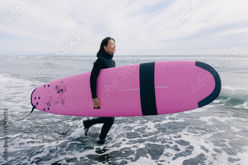 Photography Extreme surfer woman in wetsuit with surfboard go to winter surfing in Atlantic ocean Kamchatka Russia