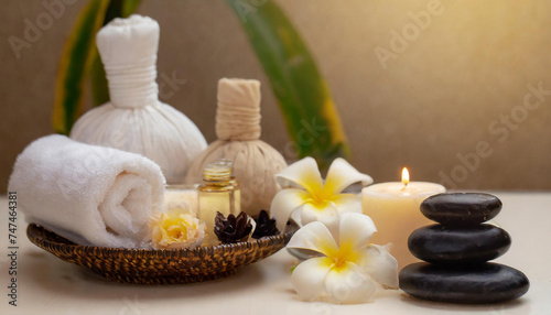 Light spa still life with candles, plumeria, oil, massage stones and towels on neutral background