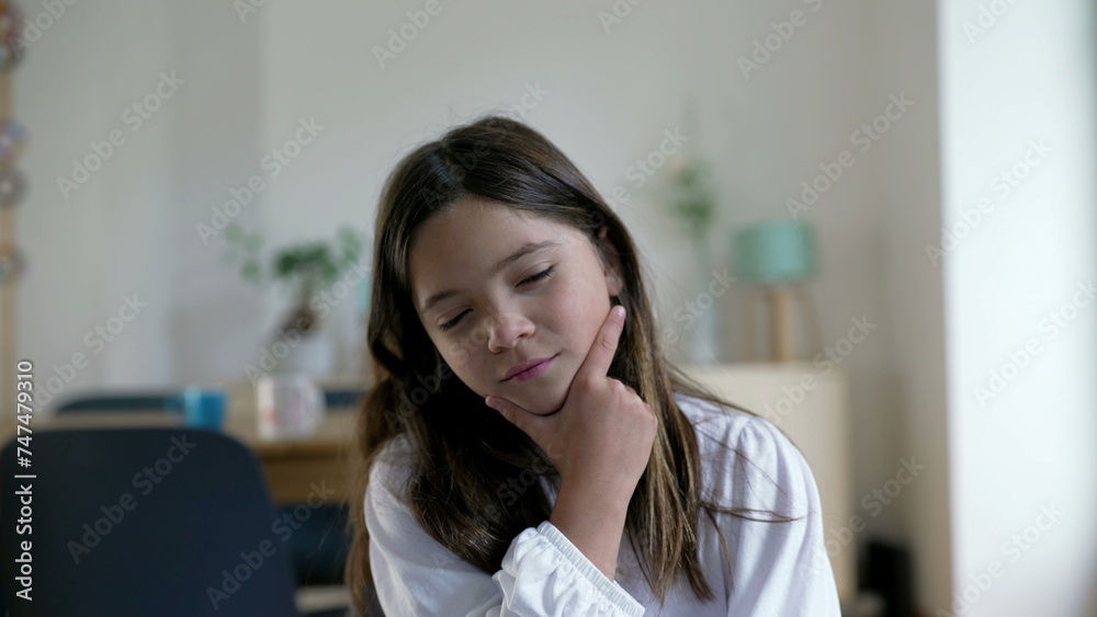 Thoughtful little girl in deep mental reflection pondering decision with hand in chin, portrait face close-up of child seeking answers Thoughtful little girl in deep mental reflection pondering decision with hand in chin, portrait face close-up of child seeking answers