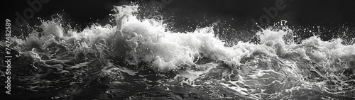 A dramatic black and white image capturing the powerful surge of ocean waves, showing detailed water textures and splashes