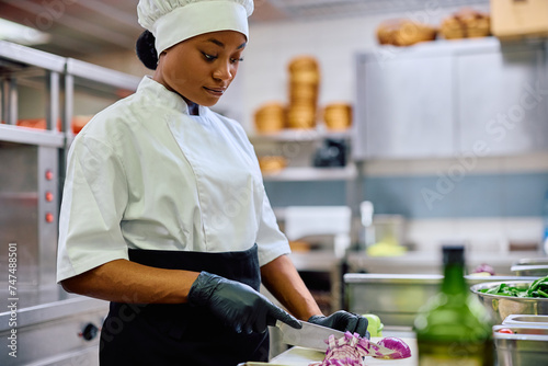 Black female chef preparing food while working in kitchen.