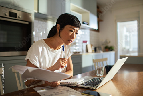 Woman doing bills with laptop at home photo