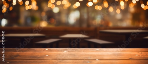A wooden table is seen in the foreground, with a blurred background created by the soft glow of restaurant lights. The focus is on the texture and simplicity of the table against the abstract backdrop