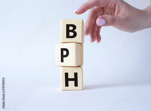 BPH - Benign Prostatic Hyperplasia symbol. Wooden cubes with word BPH. Businessman hand. Beautiful white background. Medical and BPH concept. Copy space.