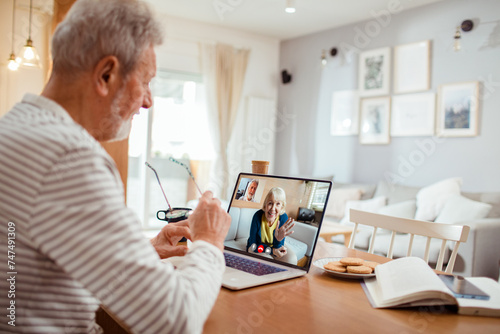 Senior man talking to wife on video call from home photo