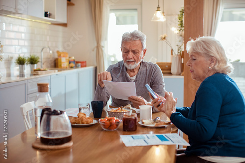 Elderly couple reading bills at the kitchen table