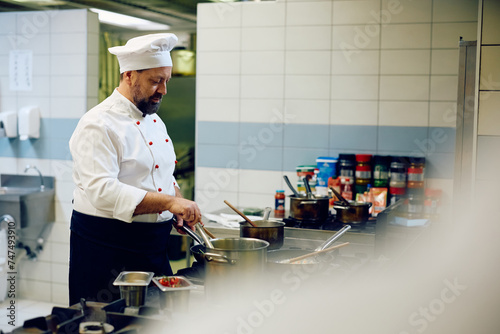 Male chef cooking dish while working in kitchen in restaurant.