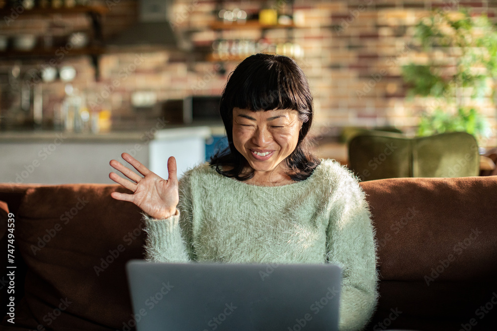 Smiling woman gesturing at laptop on the couch at home Smiling woman gesturing at laptop on the couch at home
