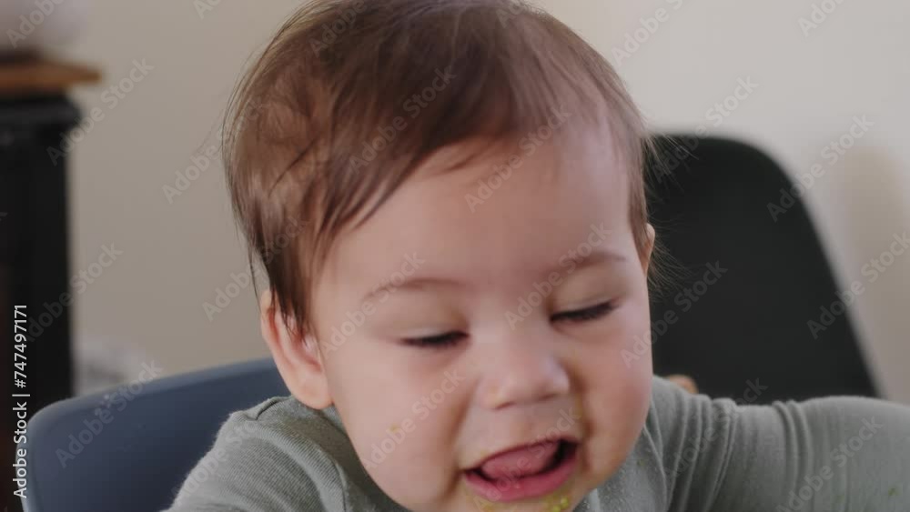 Baby boy covered in avocado plays with his food