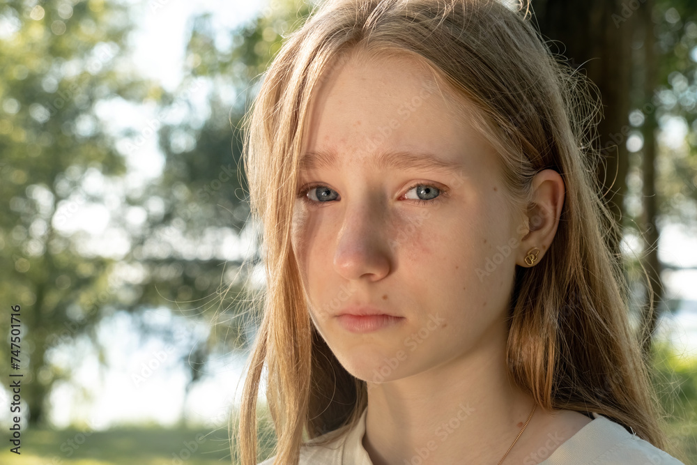 Serious girl conveys deep sense of sadness looking at camera. Unhappy child with loose hair feels lonely in park on sunny day Serious girl conveys deep sense of sadness looking at camera. Unhappy child with loose hair feels lonely in park on sunny day