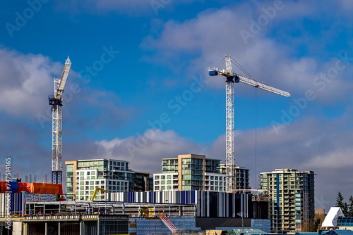 Construction site with construction cranes working on a construction complex of high-rise buildings on the background of blue cloudy sky