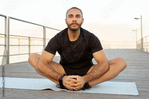 Canvas Print sporty man in activewear showcases flexibility with butterfly stretch outside
