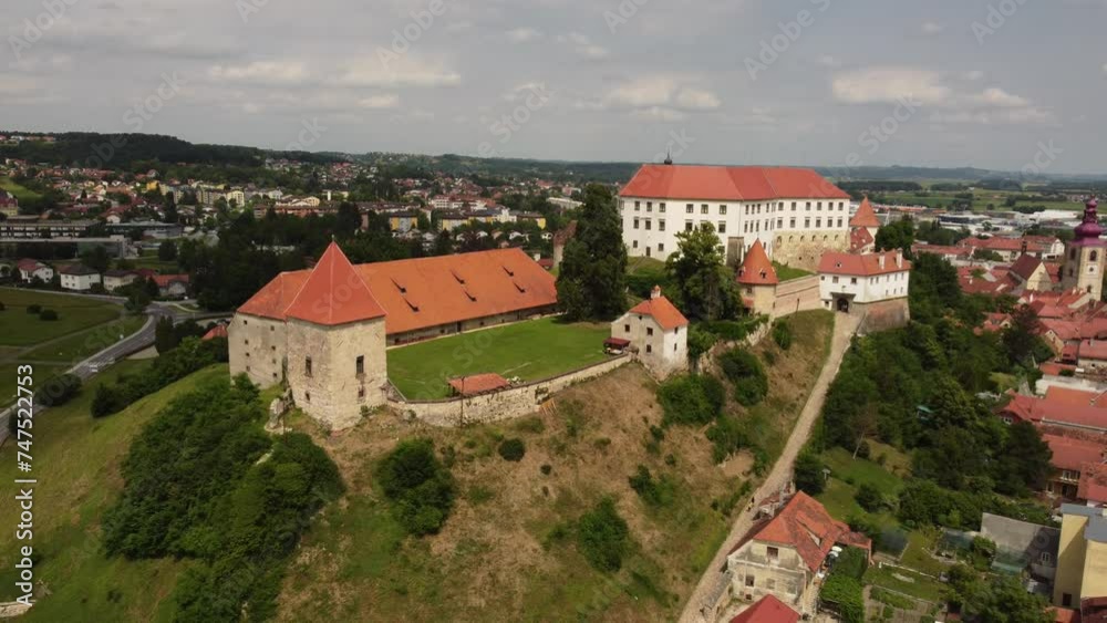 A drone films an ancient castle located on a hill. The drone moves backward smoothly. A drone films an ancient castle located on a hill. The drone moves backward smoothly.