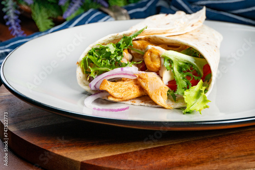 Wholegrain tortilla wraps with vegetables and chicken on a plate.