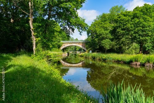 Un pont de pierre sur le canal de Nantes à Brest en été, en Bretagne, évoque un charme intemporel, offrant une vue pittoresque de la région.