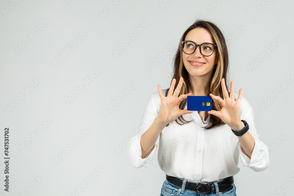 Optimistic young woman with glasses holding a blue credit card between fingers Optimistic young woman with glasses holding a blue credit card between fingers