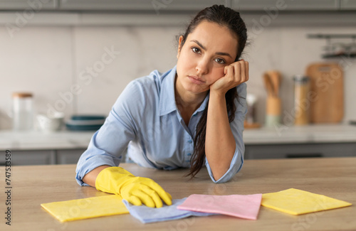 Tired young woman cleaning, showing fatigue after household chores photo